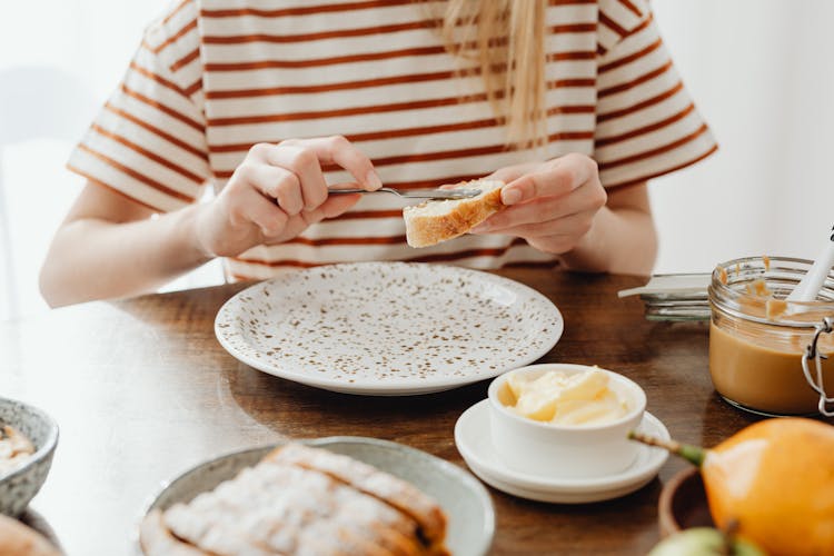 Person Spreading Butter On Sliced Bread