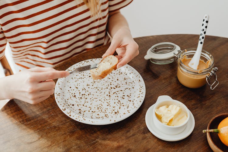 Person Spreading Butter On Sliced Bread