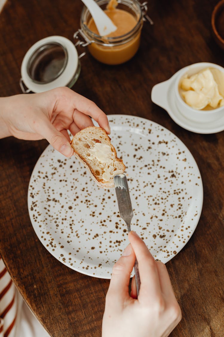 Person Spreading Butter On Sliced Bread