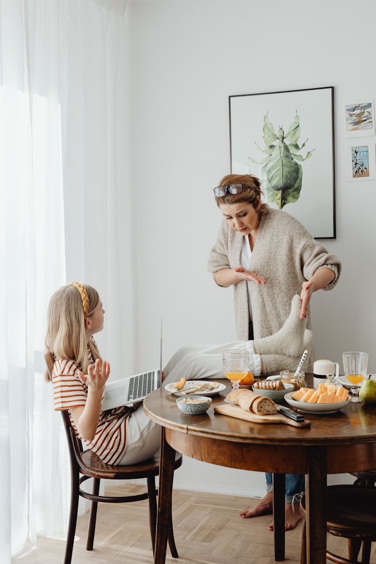 Mother Scolding Her Daughter For Putting Feet On The Table 