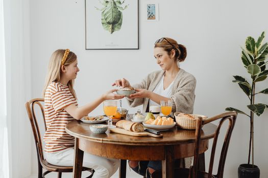 A mother and daughter share a joyful breakfast at home, highlighting family bonding.