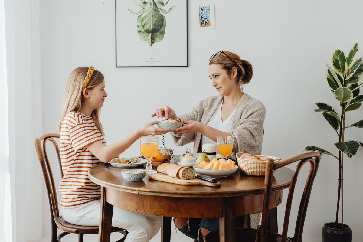 Moment familial partagé à table avec lumière naturelle chaude, convivialité et douceur