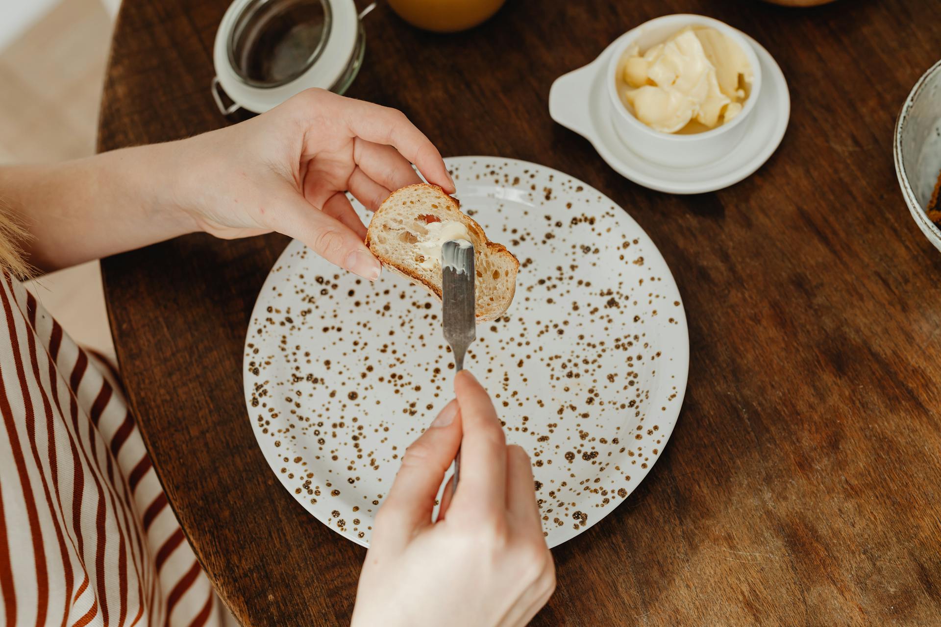 Close-up of a person spreading butter on bread for a delicious breakfast.