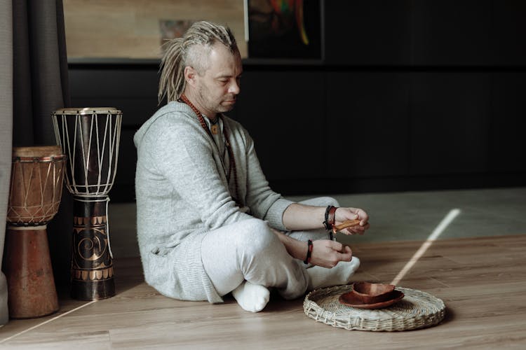 A Man In Gray Hoodie Lighting A Palo Santo