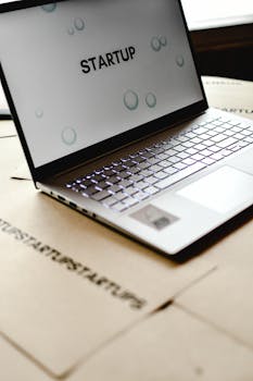 Close-up of a laptop with 'startup' screen on cardboard desk, symbolizing innovative workspaces.
