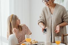 Two women enjoy a casual breakfast at home, chatting and sharing food.