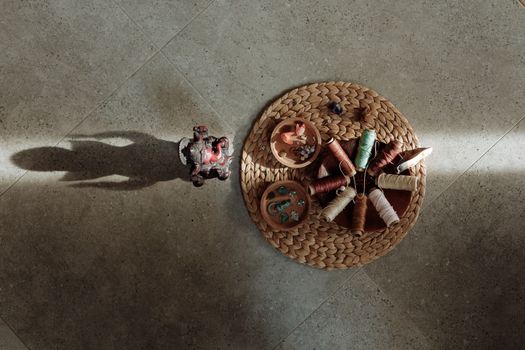 Top view of colorful threads and a Hindu figurine on a textured surface.