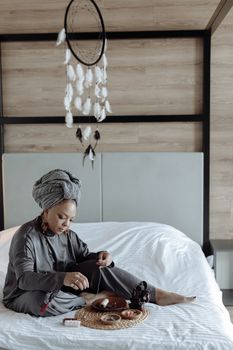 Peaceful scene of a woman meditating with a dream catcher above her in a cozy bedroom setting.