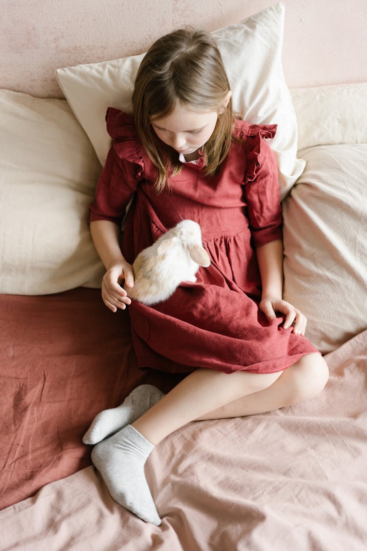 Young Girl On A Bed Petting A Rabbit