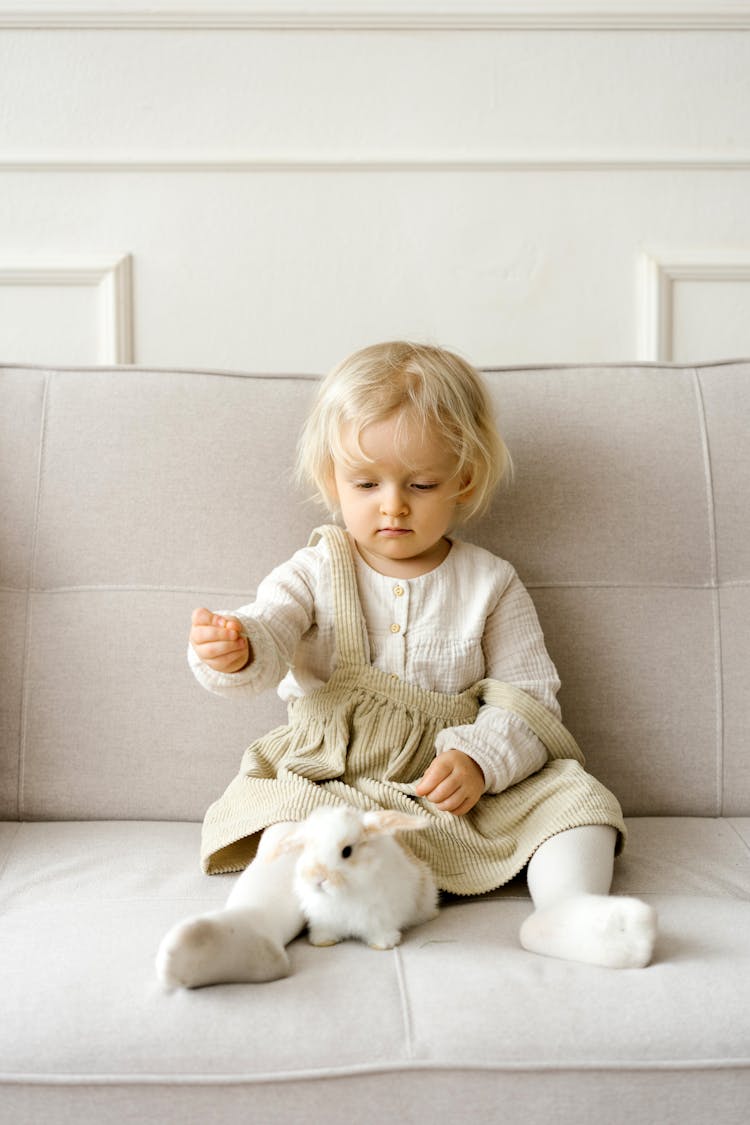 A Toddler Sitting On Sofa With A Bunny