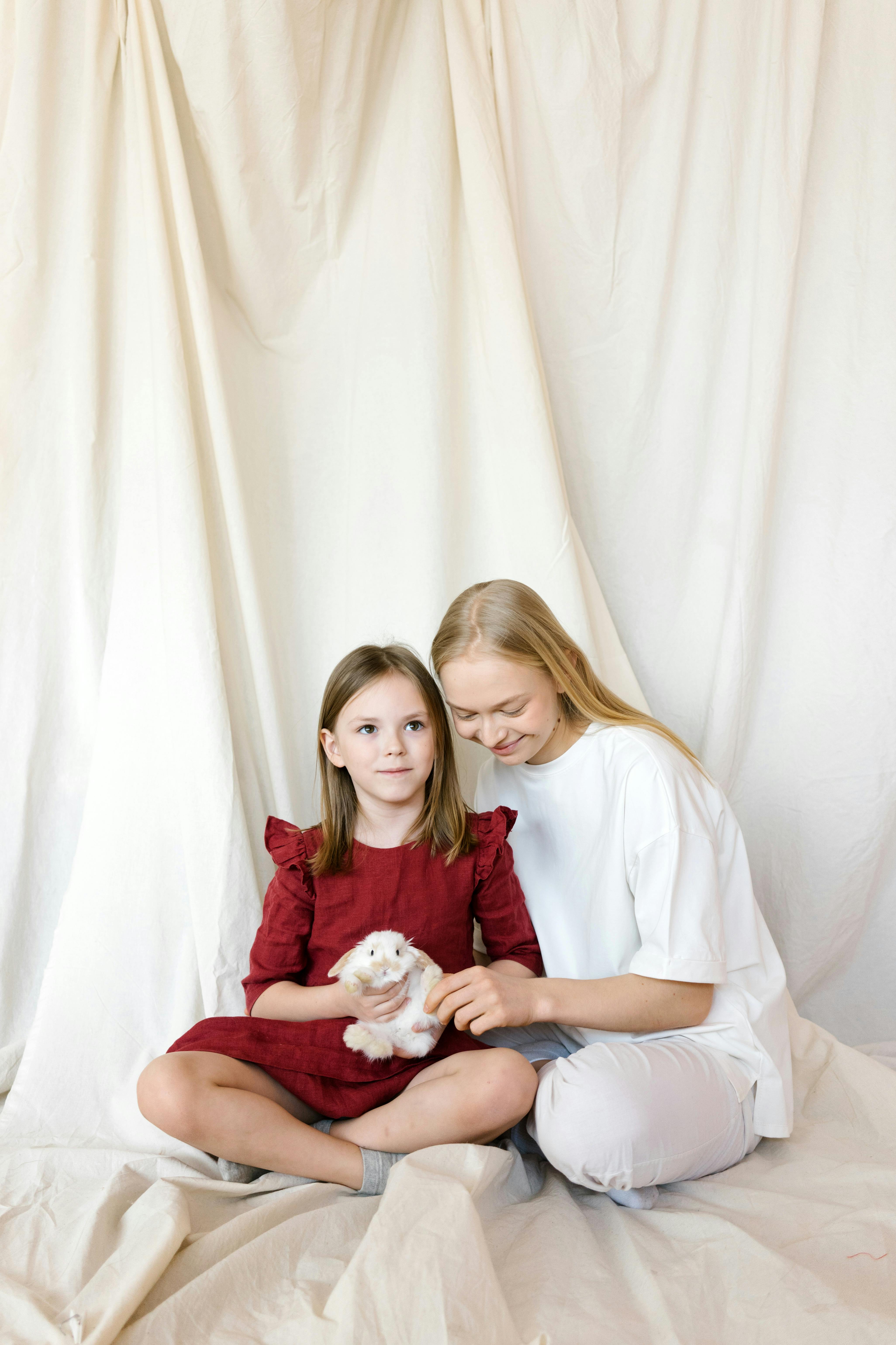 a mother and daughter sitting together while petting a bunny