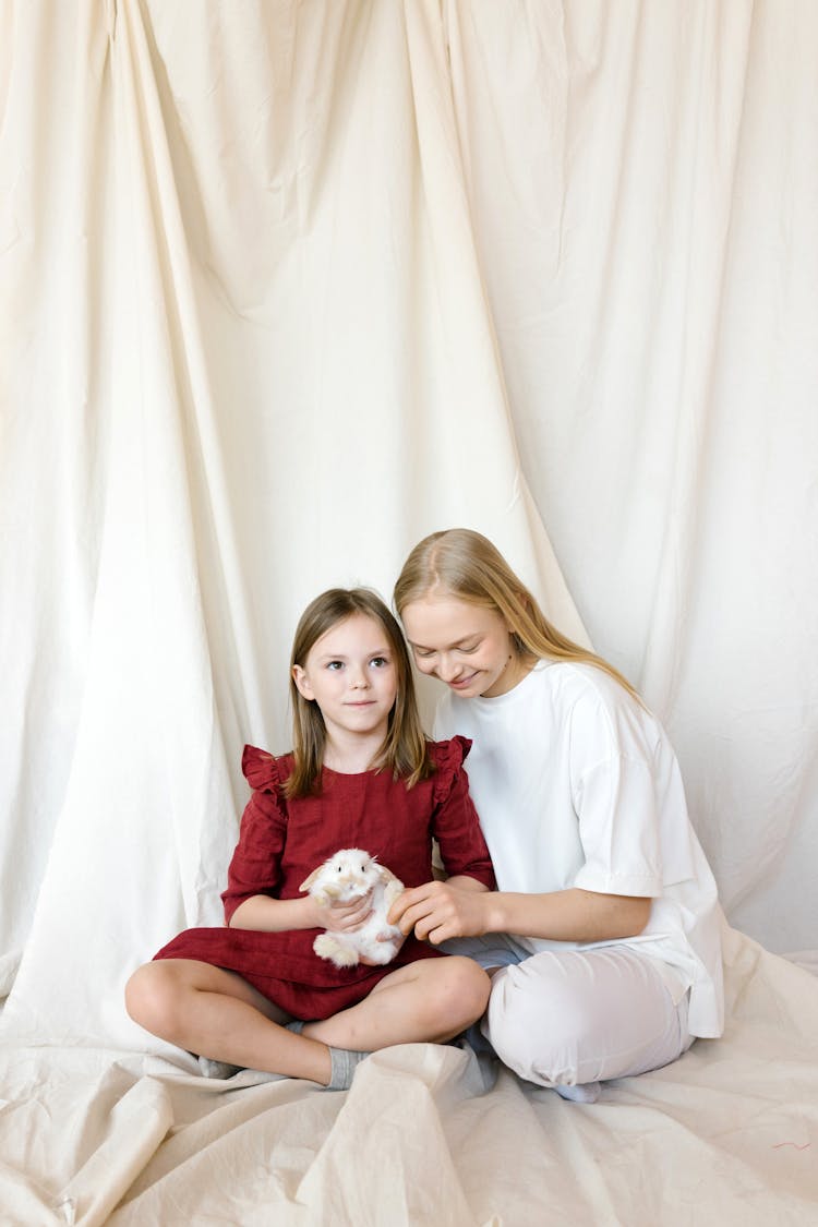 A Mother And Daughter Sitting Together While Petting A Bunny