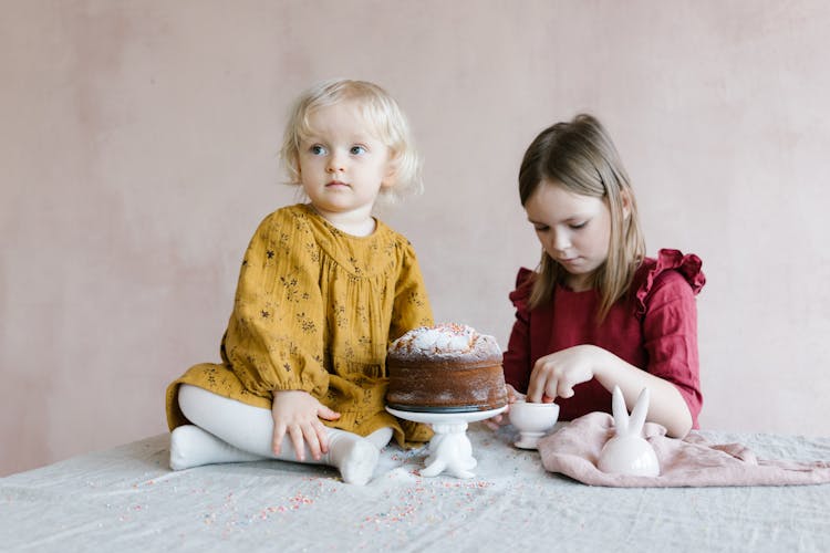 Two Girls Near A Cake On A Table