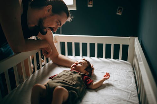 Free Caring father stroking baby in bed Stock Photo