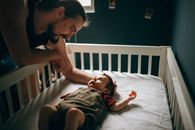 Caring father stroking baby in bed