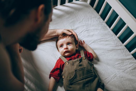 Anonymous man stroking baby in cot