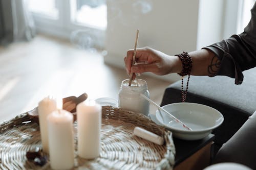 Person Holding White Plastic Straw in Front of Lighted Candles