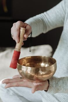 Person holding a brass singing bowl, ready for meditation with mallet.