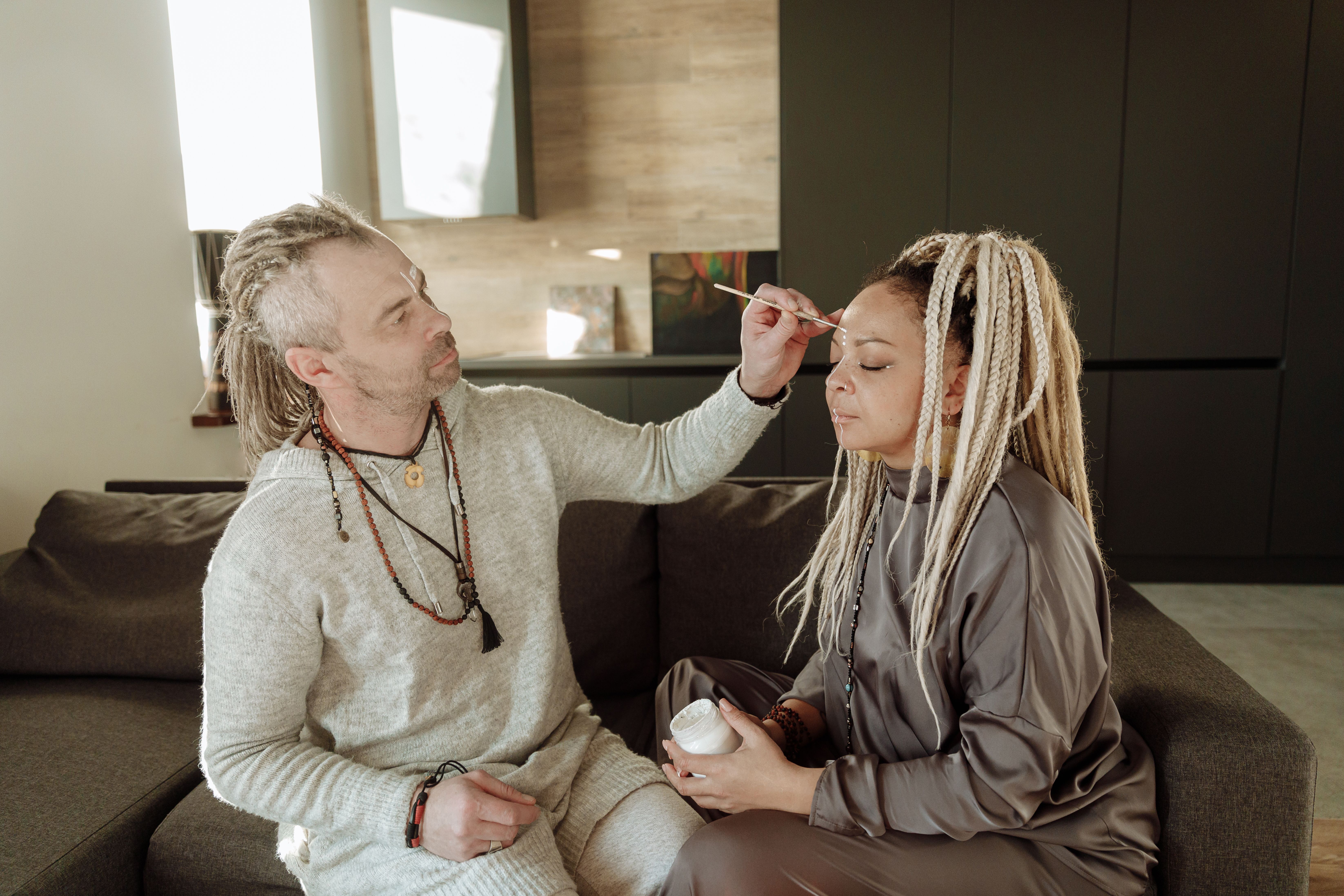 https://www.pexels.com/photo/man-and-woman-sitting-on-the-couch-while-putting-face-paint-6957516/