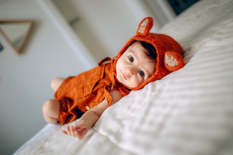 Cute Baby In Costume Lying On Bed