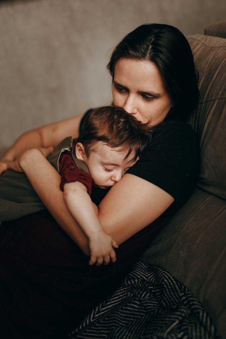 Mother Hugging Sleeping Son On Sofa