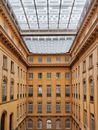 Tall classic building with transparent glass ceiling and different windows in bright daylight