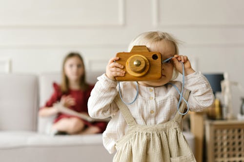 Free Toddler Playing with a Wooden Camera Stock Photo