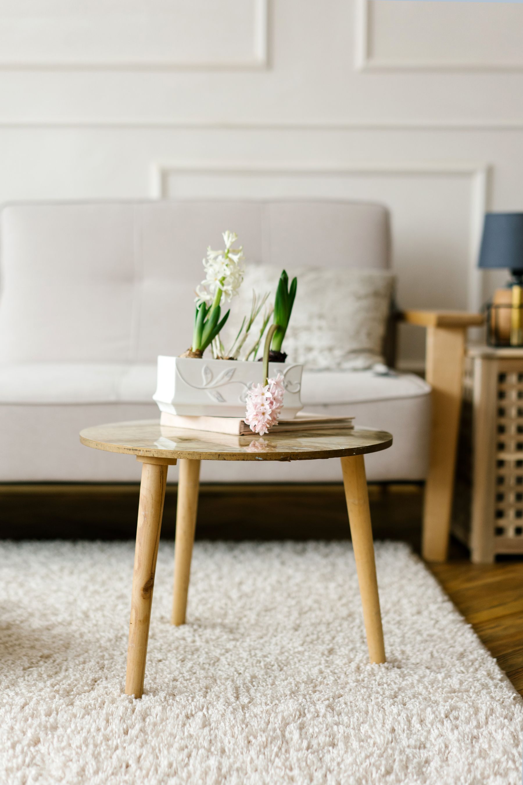 Bright living room with a soft rug, pale sofa and white flowers on the coffee table