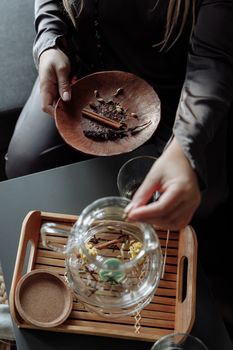 Close-up of hands preparing herbal tea with spices in a cozy setting.
