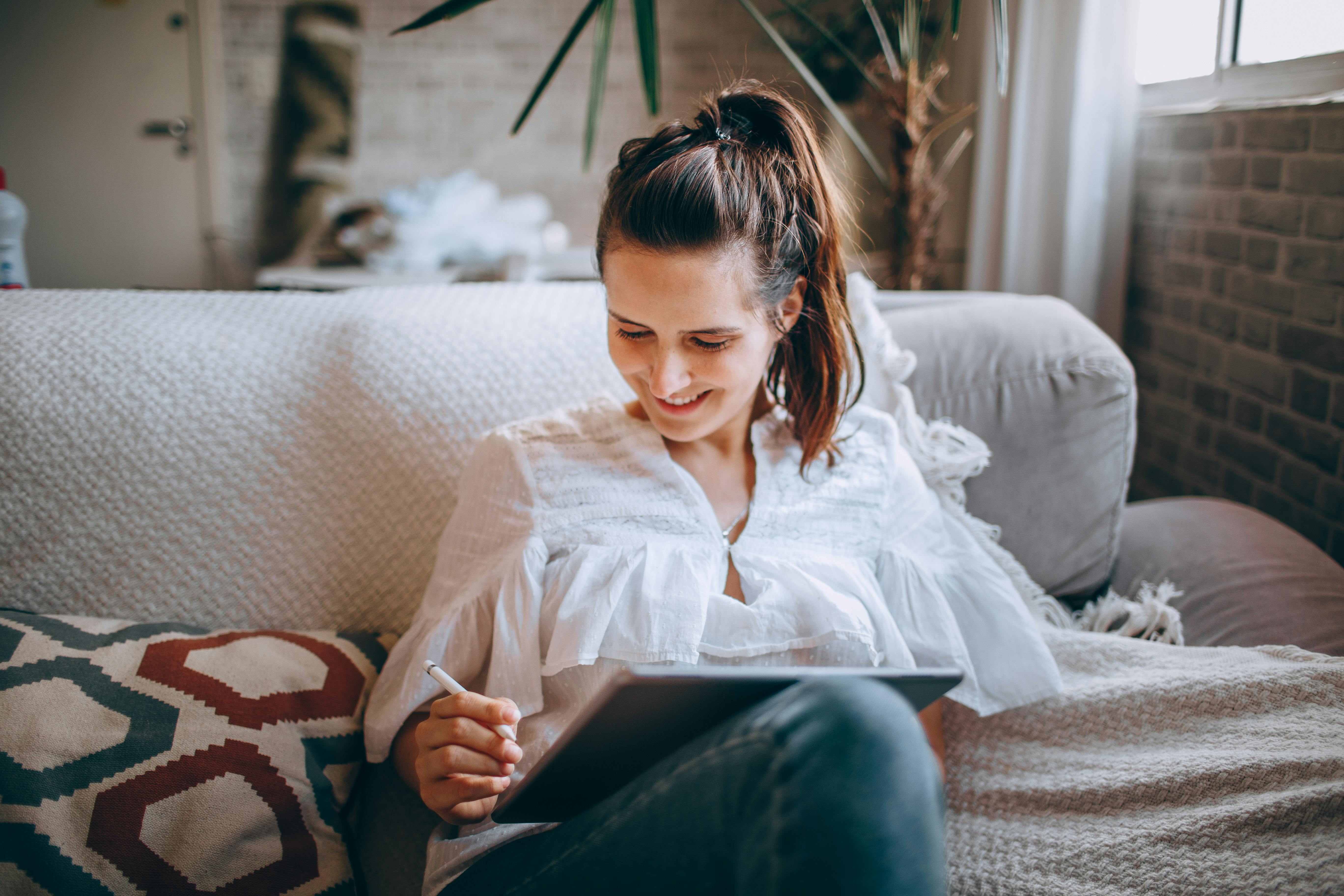 smiling woman using tablet on sofa