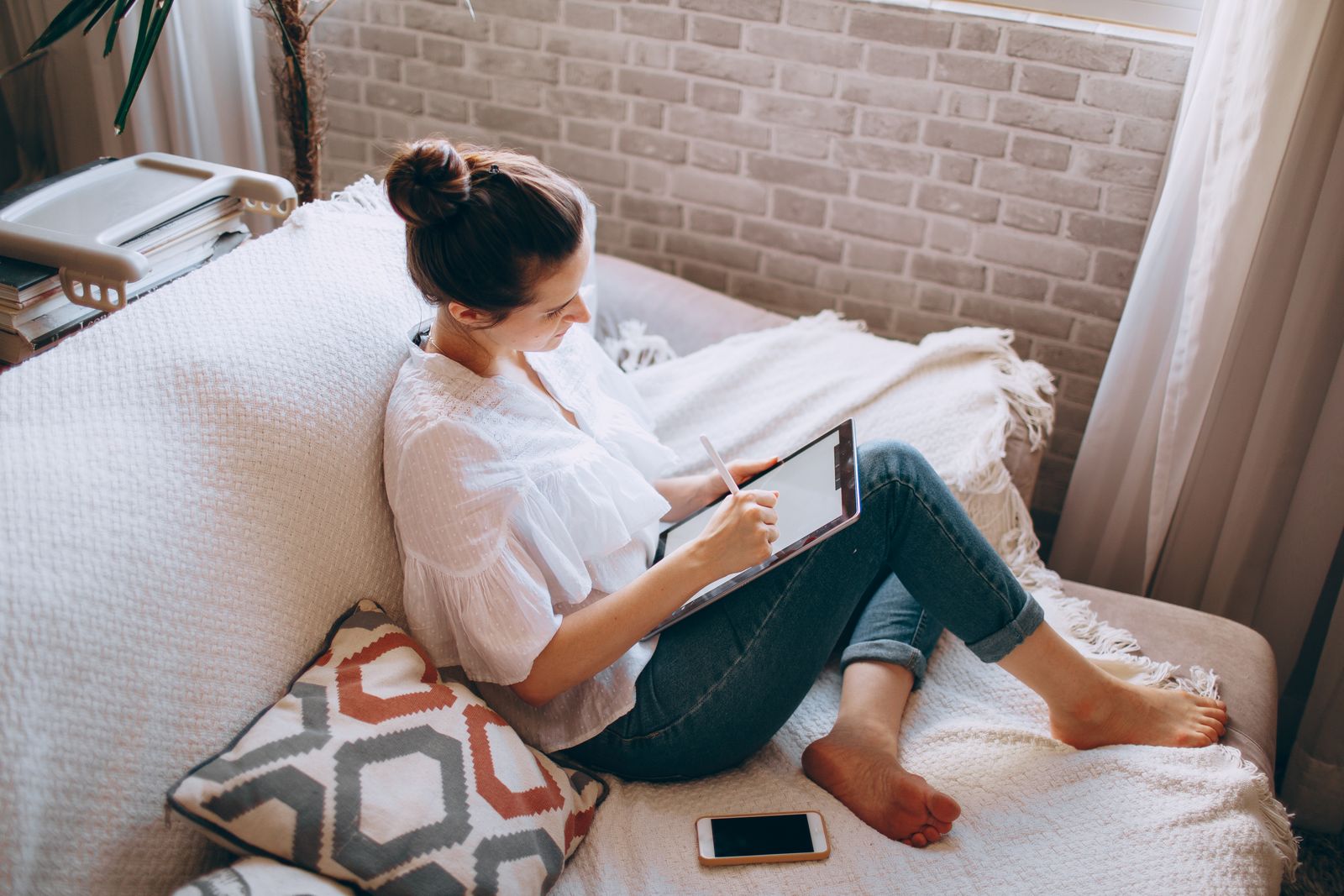 Woman relaxing on a lounge reading an ebook on an iPad in a bright neutral living room