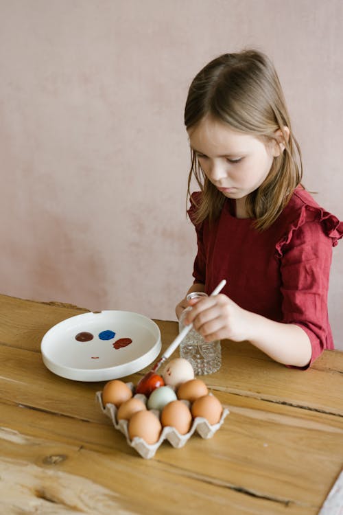 Cute Girl in Red Dress Painting the Eggs