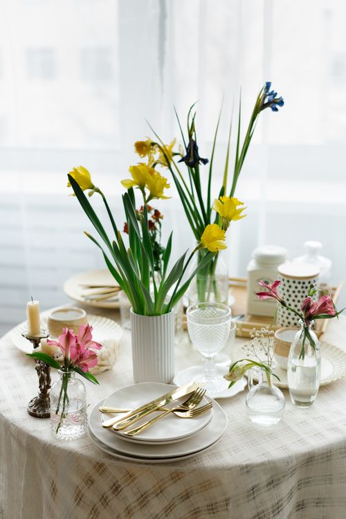 Free A beautifully arranged dining table with daffodils and elegant tableware, perfect for a spring gathering. Stock Photo