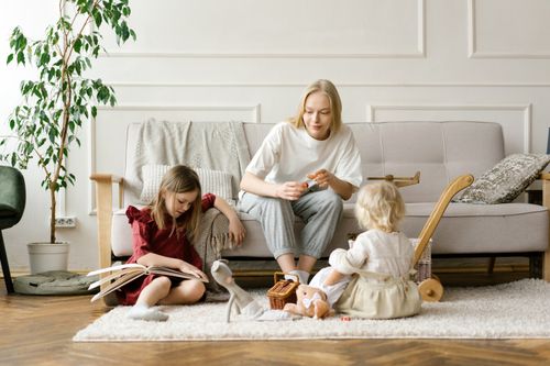 Free A mother and her daughters enjoying playtime in a stylish living room setting. Stock Photo