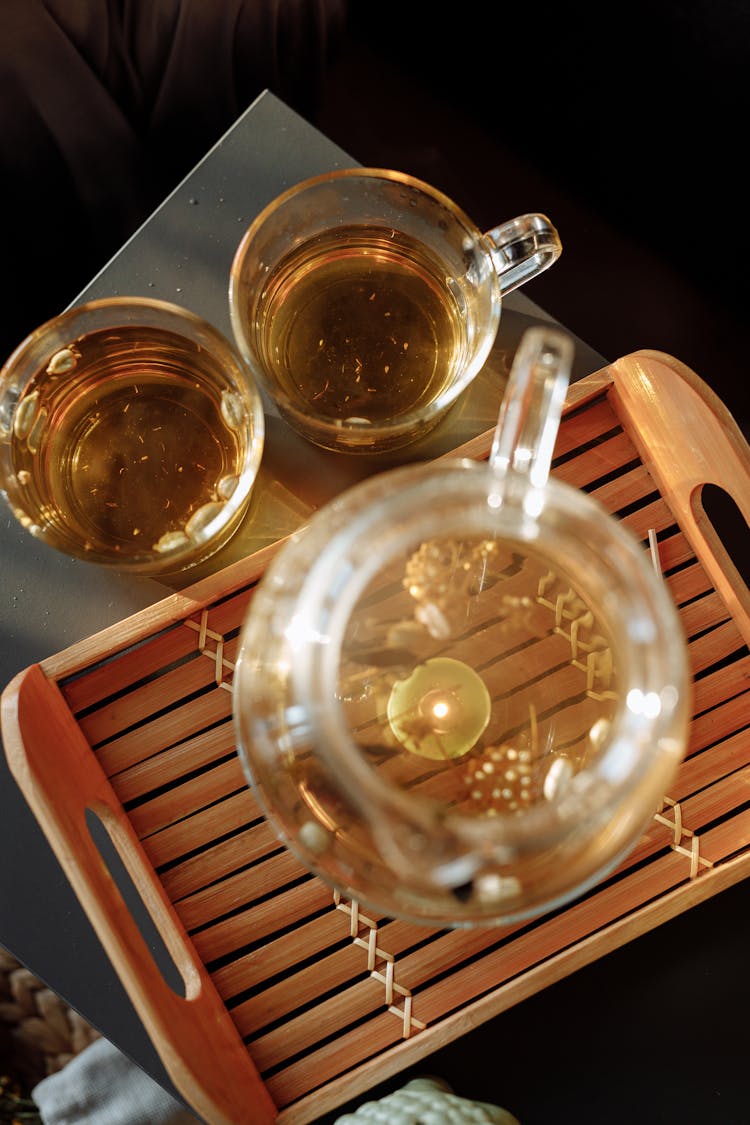 A Pitcher Of Tea On A Wooden Tray Beside Glass Mugs