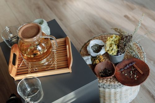 Free A glass teapot with herbal tea and dried flowers on a wooden tray indoors. Stock Photo