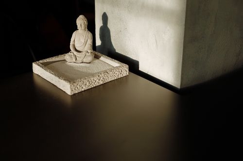 Free Minimalist still life of a Buddha statue casting a shadow on a black surface. Stock Photo