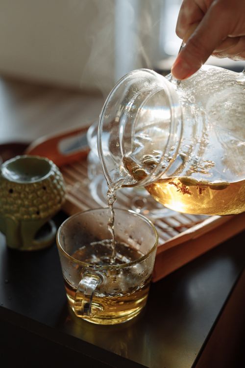 Free Close-up shot of tea pouring from a glass teapot into a teacup, capturing the essence of a relaxing tea time. Stock Photo