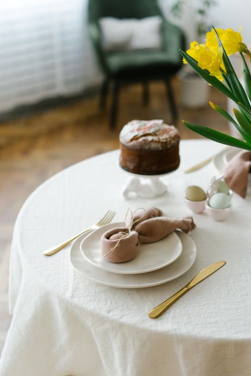 Free Beautifully arranged Easter table setting featuring a cake, daffodils, and elegant tableware. Stock Photo