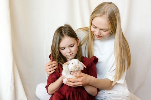 Free A mother and daughter share a tender moment while petting their cute rabbit. Stock Photo