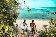 冲浪者沿着郁郁葱葱的小路，前往巴厘岛令人惊叹的海滩