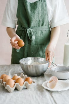 Close-up of a person preparing a baking mixture with fresh ingredients like eggs and flour.