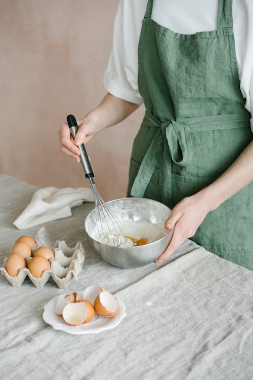 Person Mixing Eggs in a Stainless Bowl