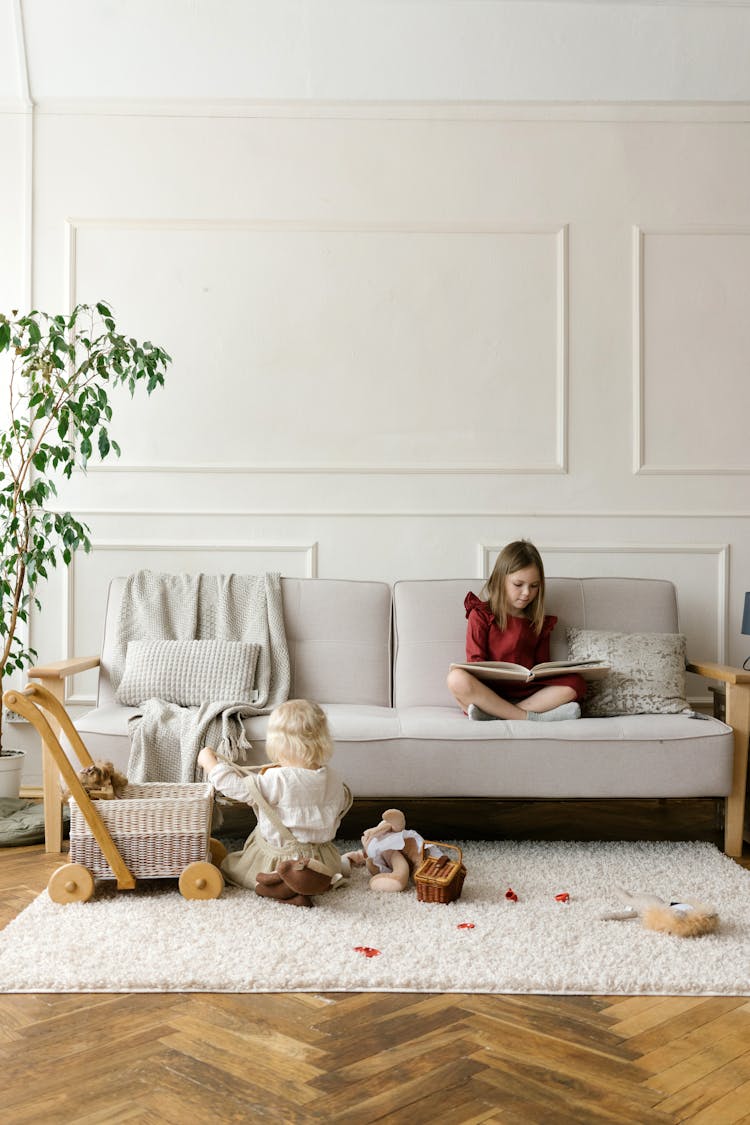 Two Girls Reading And Playing In A Living Room