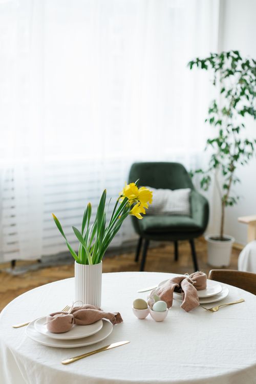 Free Sophisticated table setting featuring a ceramic vase with yellow flowers, ideal for spring themes. Stock Photo