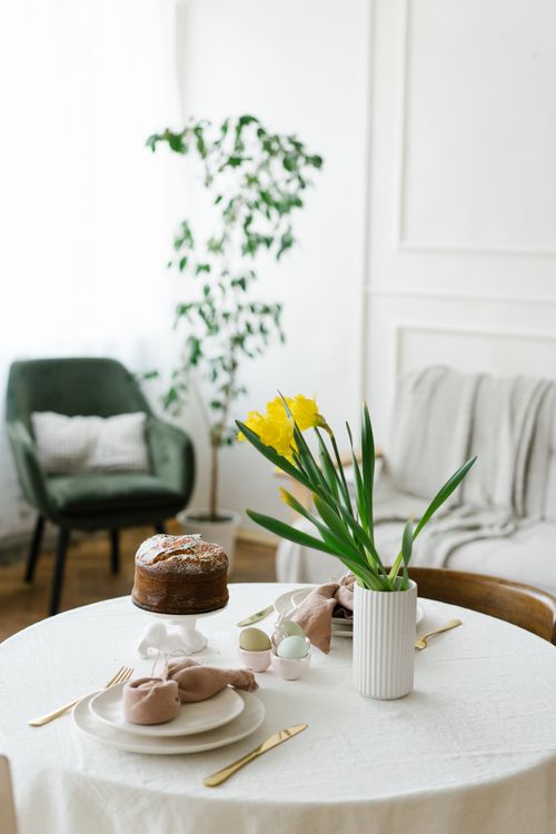 Free A beautifully arranged Easter table with cake and flowers in a sunlit living room. Stock Photo