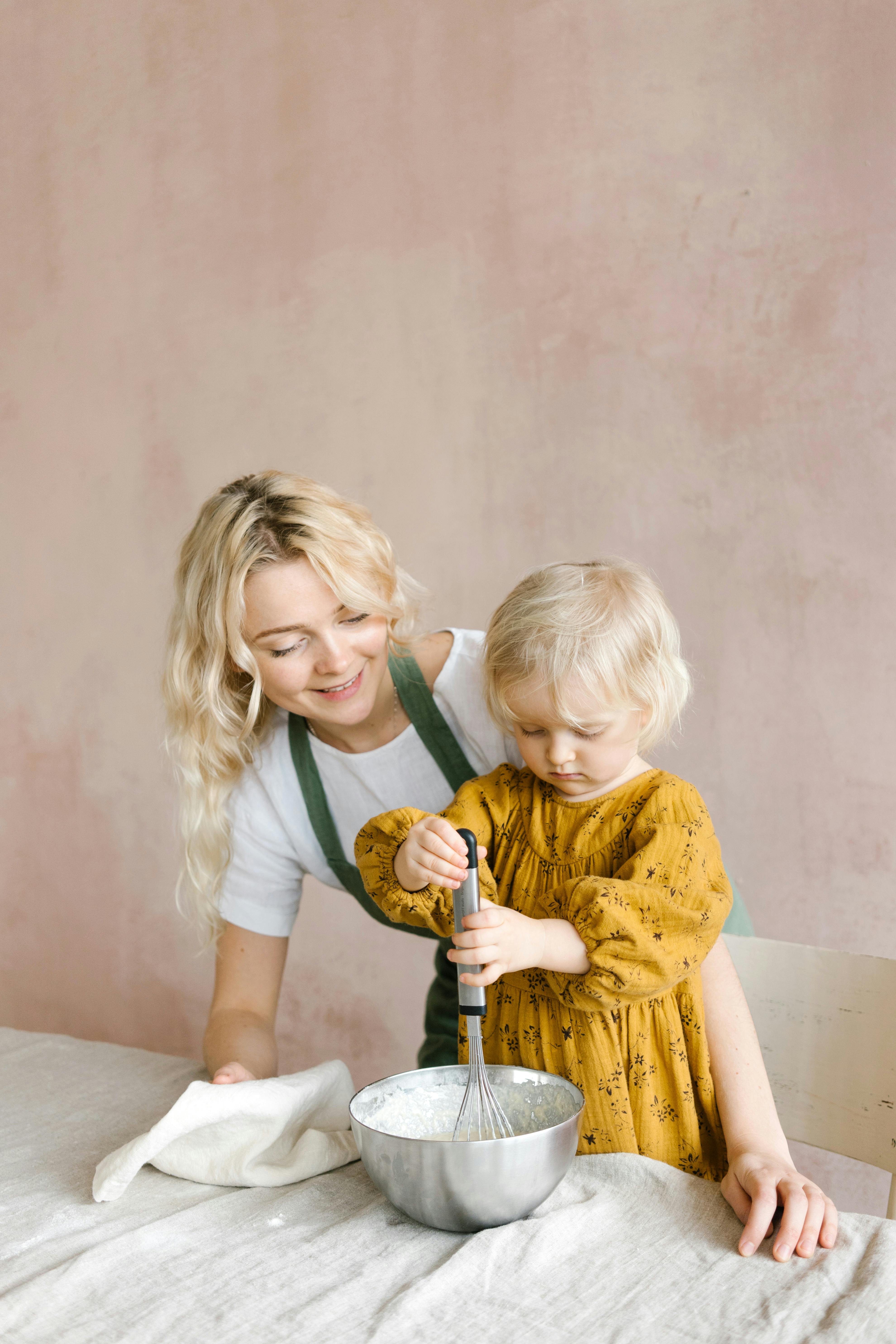 a young girl holding silver whisk