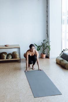Woman on yoga mat preparing for exercise at home. Calm indoor atmosphere.