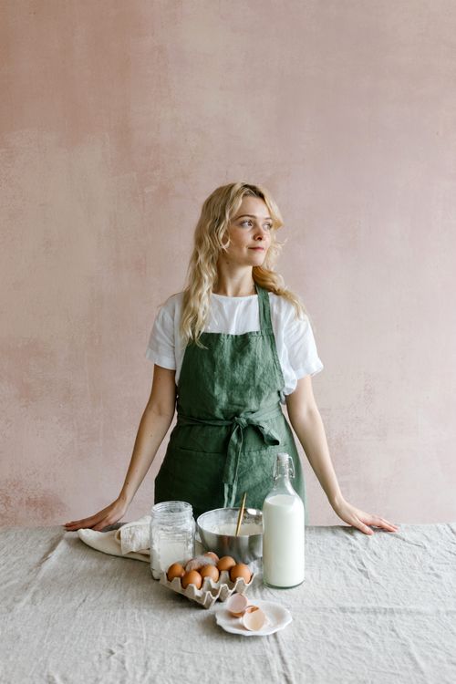 Free Caucasian woman preparing to bake with eggs and milk on a table indoors. Stock Photo