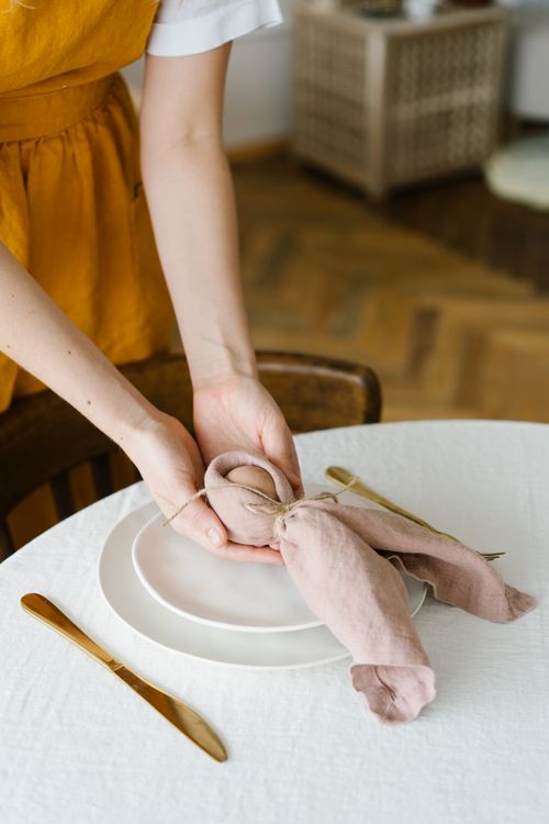 Free A close-up of a woman's hands elegantly placing an Easter-themed napkin decor on a dining table. Stock Photo
